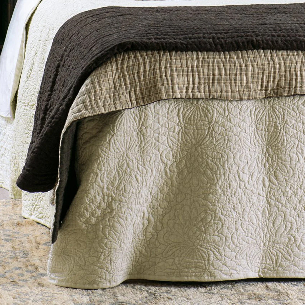 Textured bedspread in soft beige and dark brown throw on a bed.