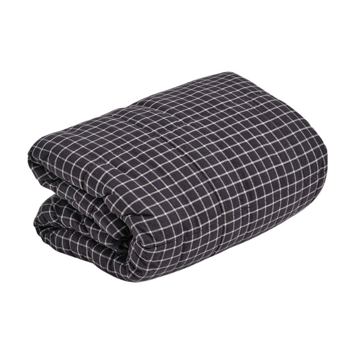Folded navy and white checkered blanket on a white background