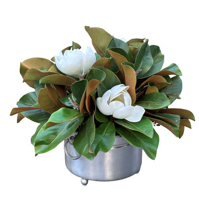 Magnolia flowers and foliage designed into a brushed silver vessel