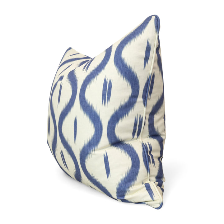 Decorative pillow with blue ikat ogee wave pattern on a white background
