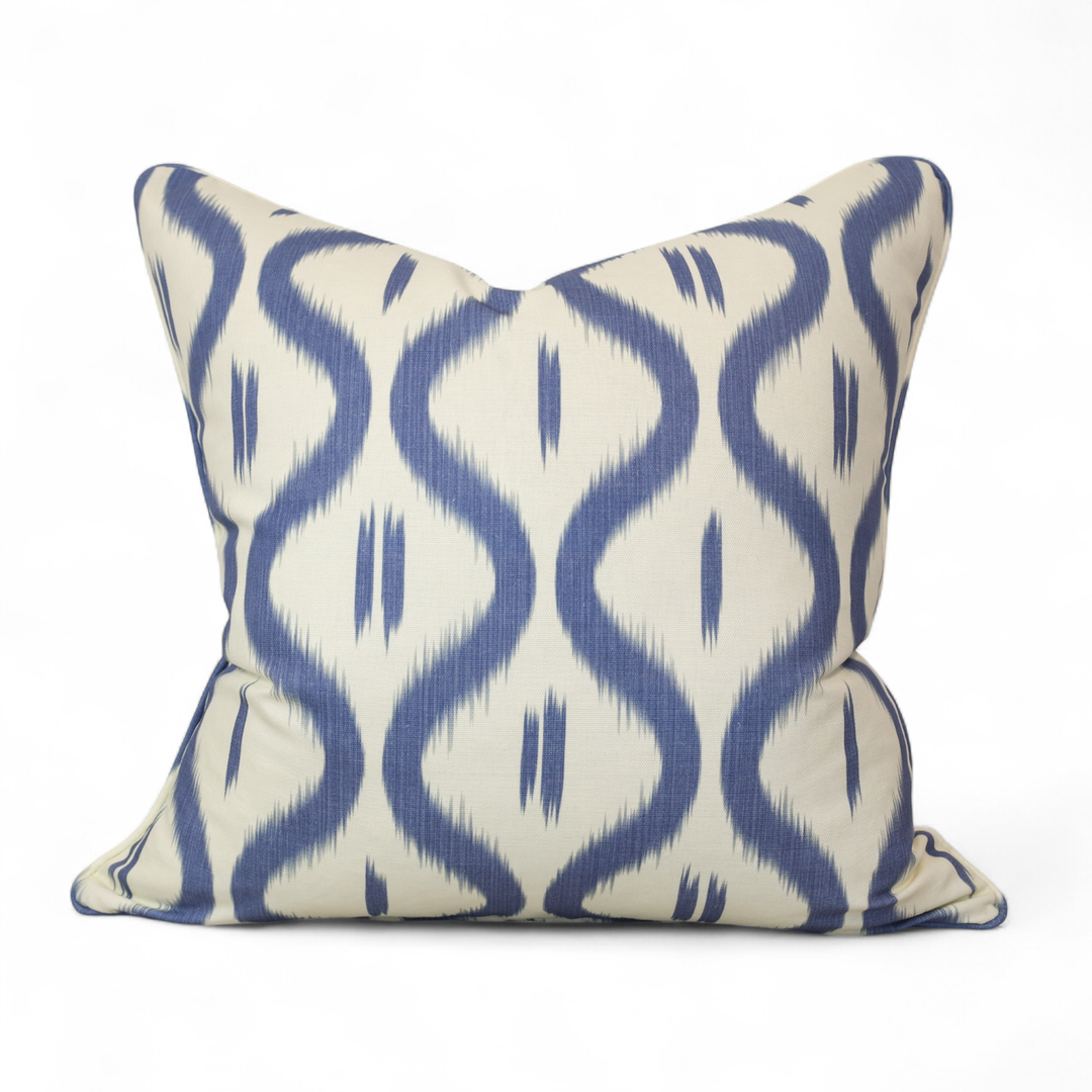 Decorative pillow with blue ikat ogee pattern on a white background