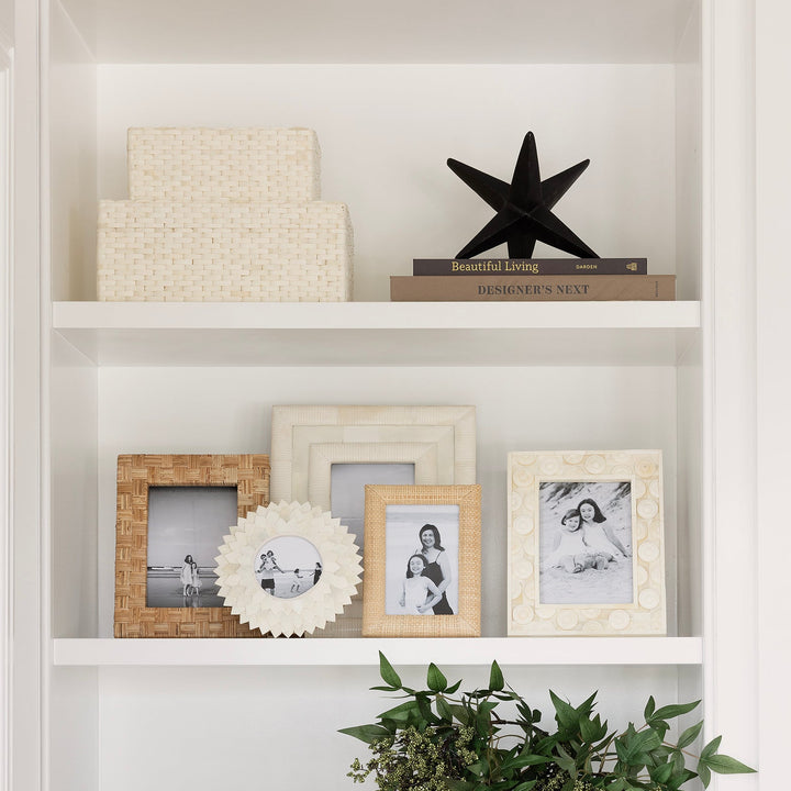Decorative bookshelf with framed photos, plants, and sculptures.