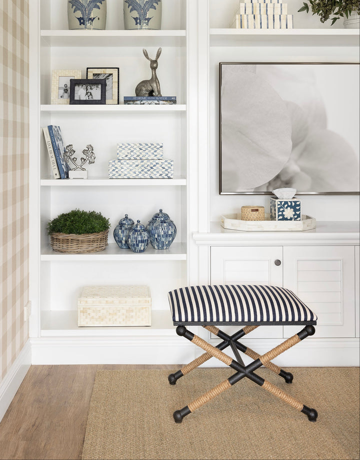 Narrow hallway with white built-in shelves, decorative items, and a striped stool.