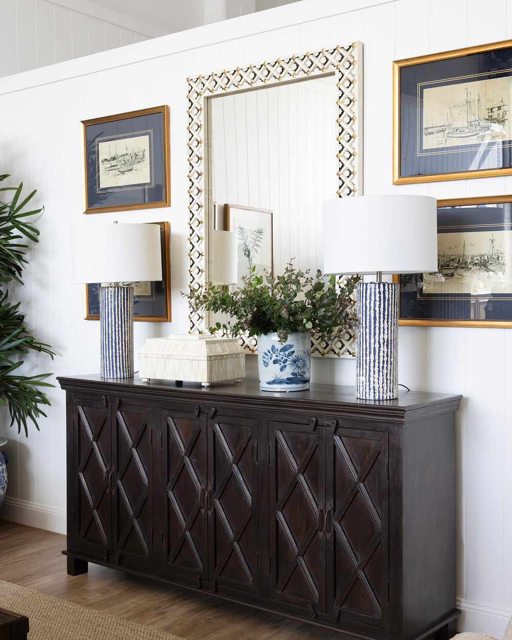 Dark wooden sideboard with decorative mirror and lamps in a room setting.