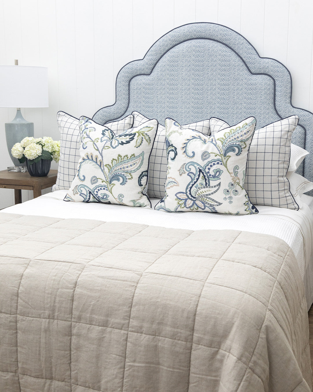 Bed with decorative pillows and a blue upholstered headboard