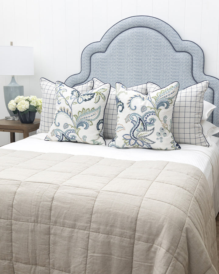 Bed with decorative pillows and a blue upholstered headboard
