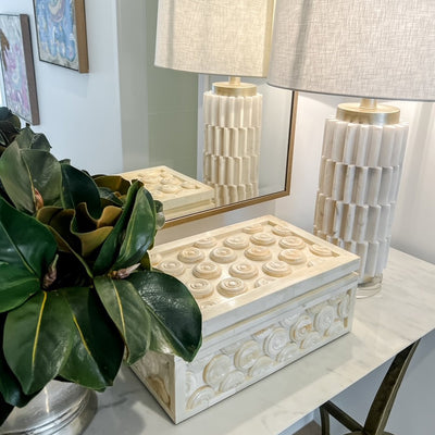 Styled image of circle bone box on a marble top console with faux plant in a silver pot and a textured lamp base and shade