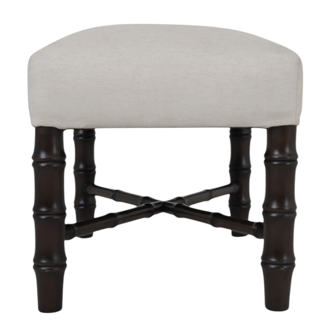 Side angle of stool with beige cushioned seat and dark wooden legs on a white background