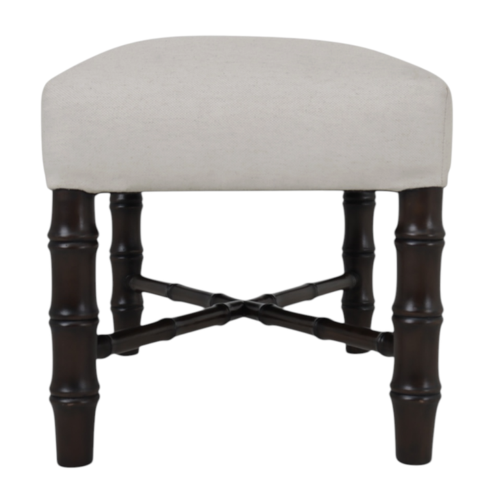 Side angle of stool with beige cushioned seat and dark wooden legs on a white background
