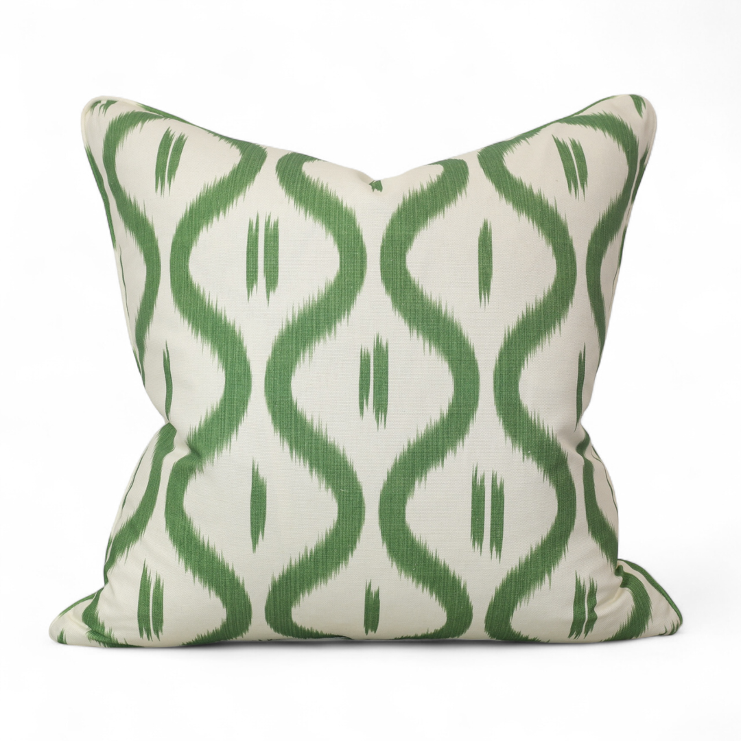 Decorative pillow with green ikat ogee pattern on a white background