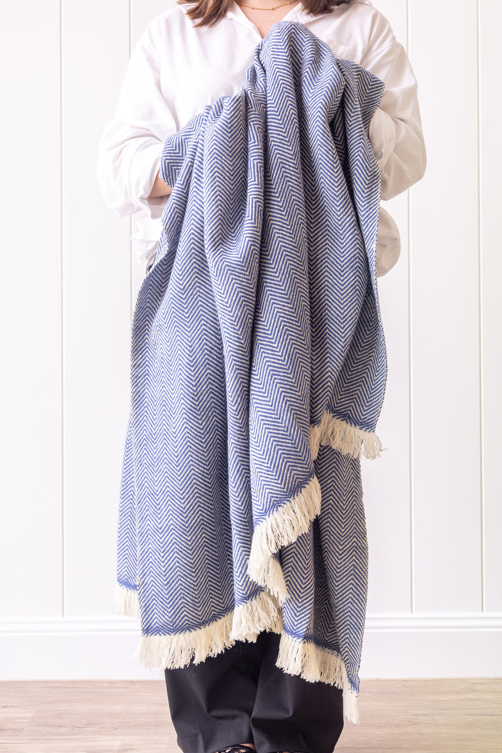 Person holding a blue and white patterned blanket against a white background