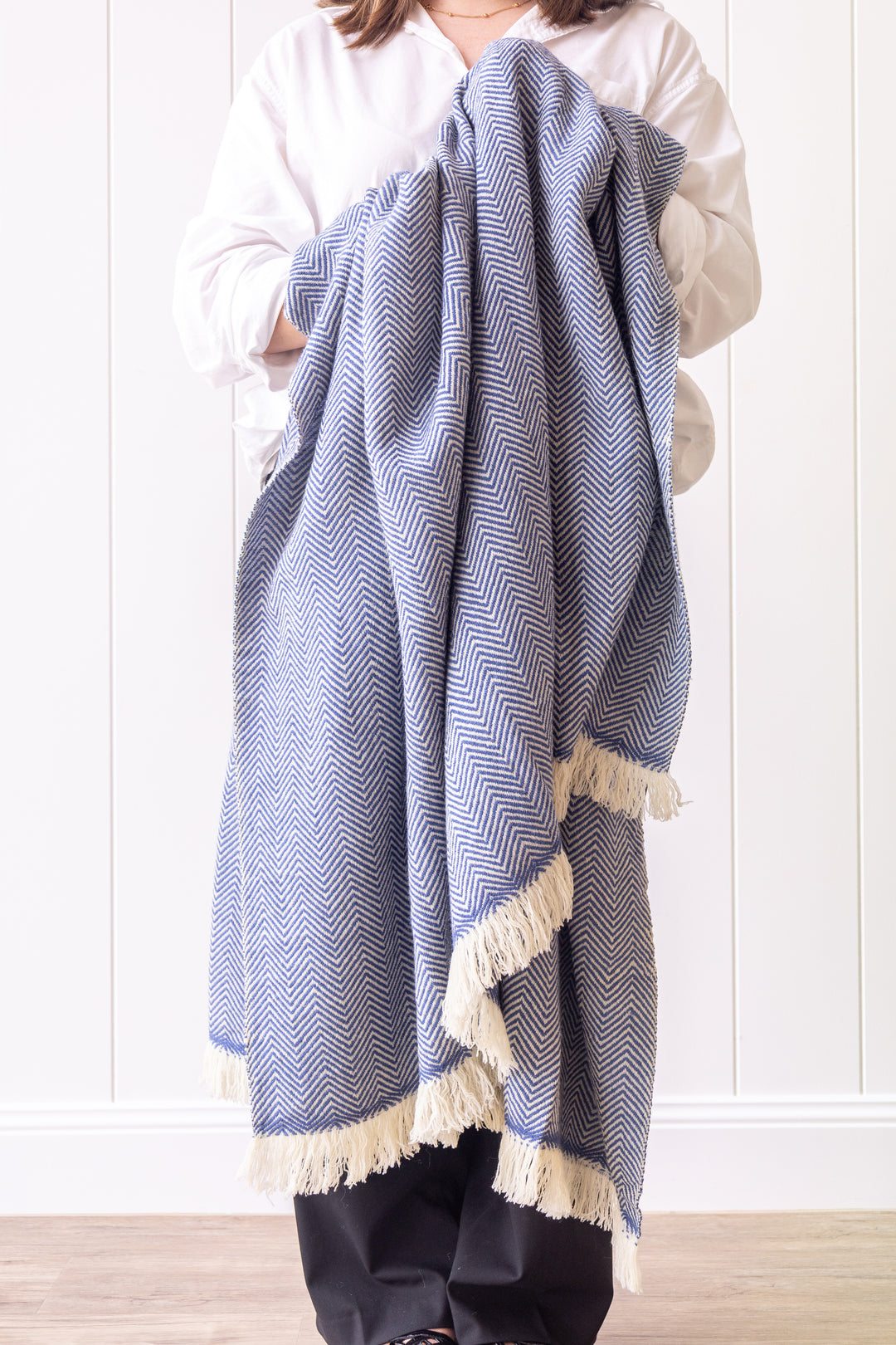 Person holding a blue and white patterned blanket against a white background