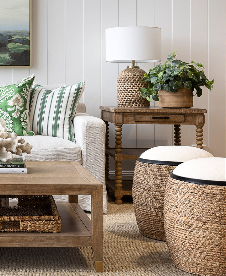 Living room with a sofa, coffee table, ottomans, and decorative items.
