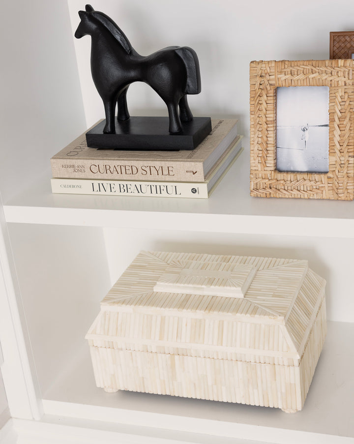 Decorative shelf with a black horse figurine, books, and a woven box.