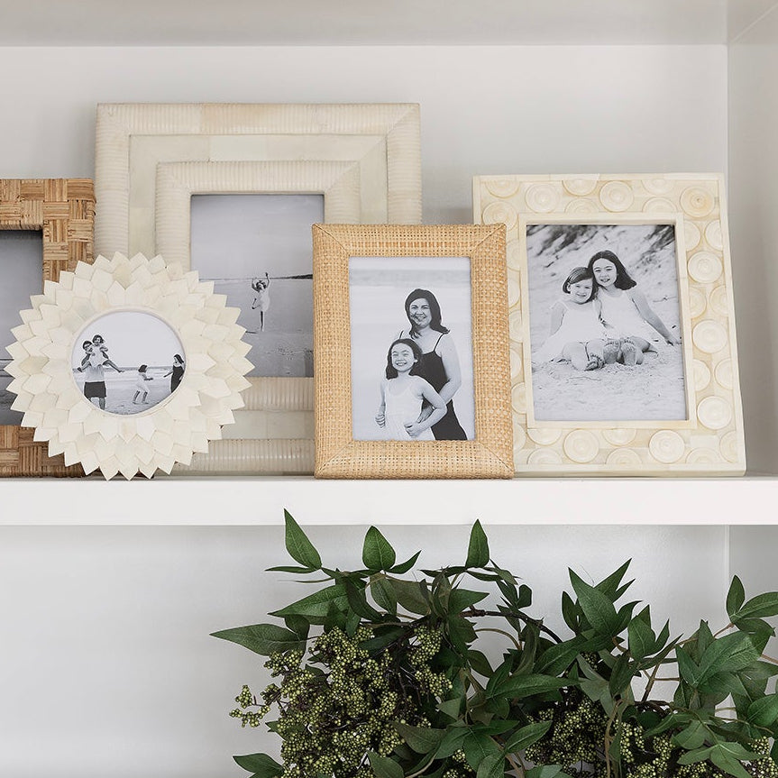 Decorative shelf with picture frames, a plant, and a decorative item against a checkered wall.