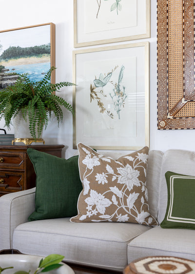 Designer print artwork styled in a lounge room setting. Artwork is hanging on a wall behind a sofa. Rich green and caramel cushions complement the artwork behind. 