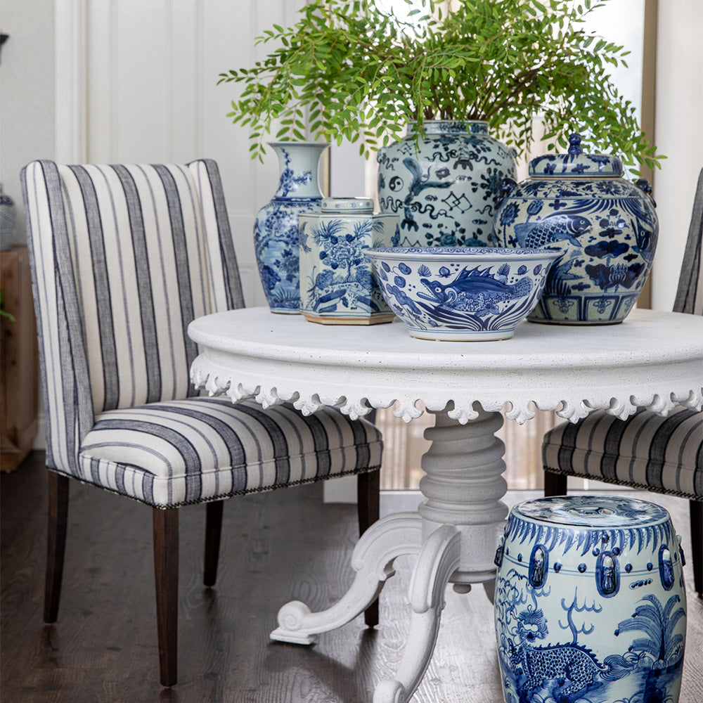 Dining room with blue and white ceramic vases and bowls on a table, striped chairs.