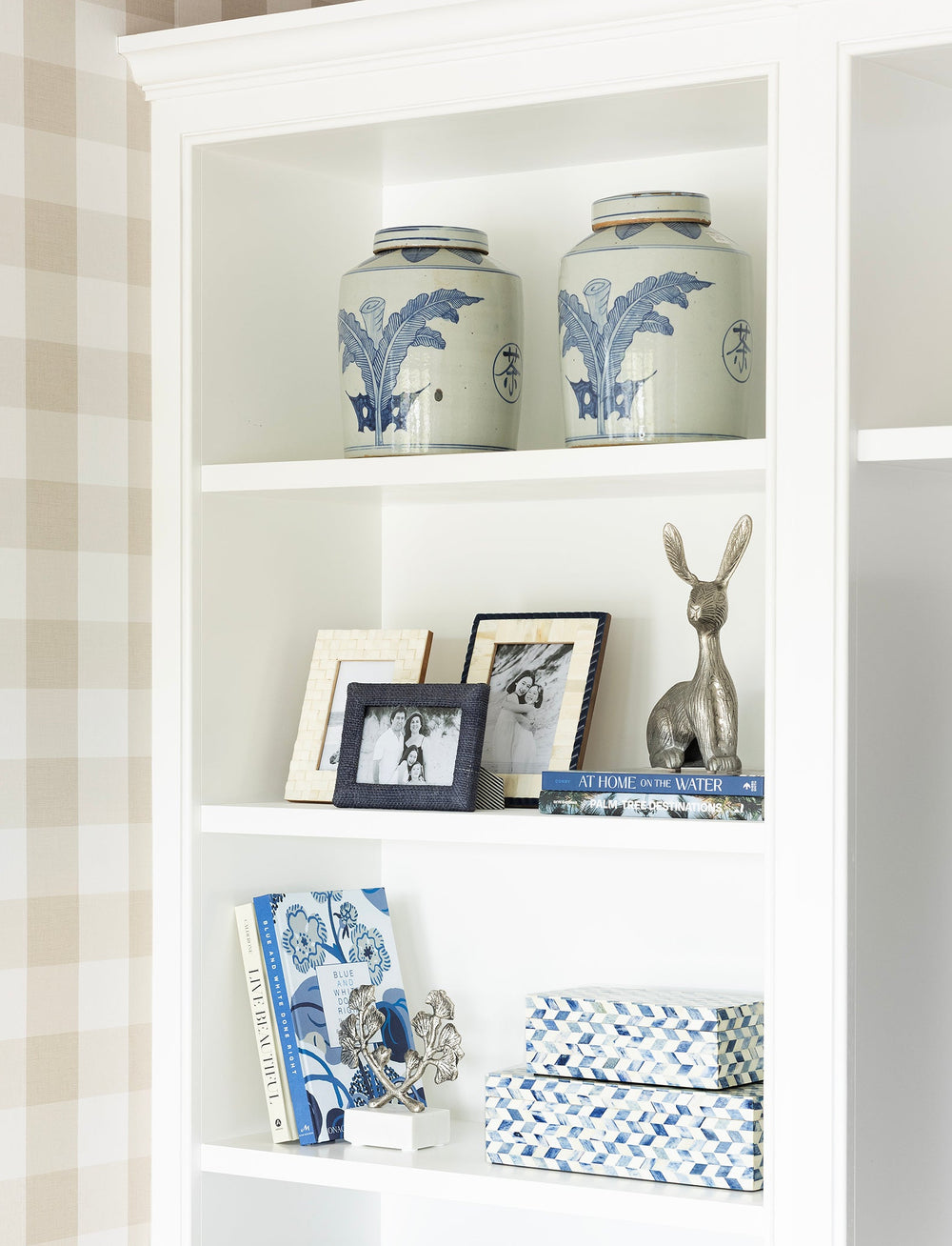 White bookshelf with decorative items against a plaid wall