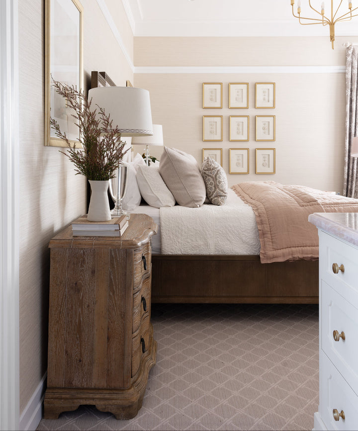 Neatly arranged bedroom with wooden nightstand, bed with pillows, and wall art.
