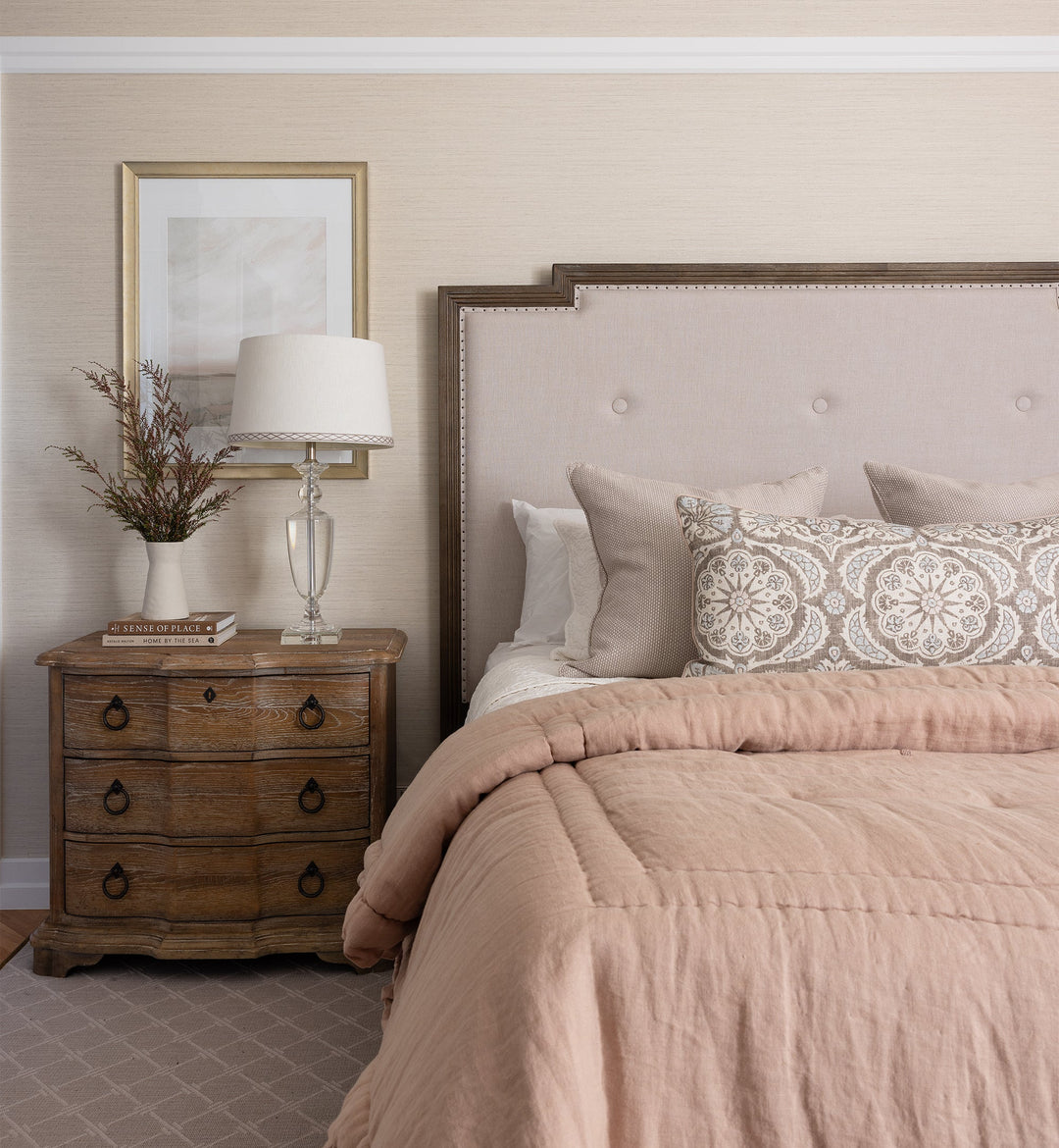 Neatly made bed with pink bedding in a bedroom setting.