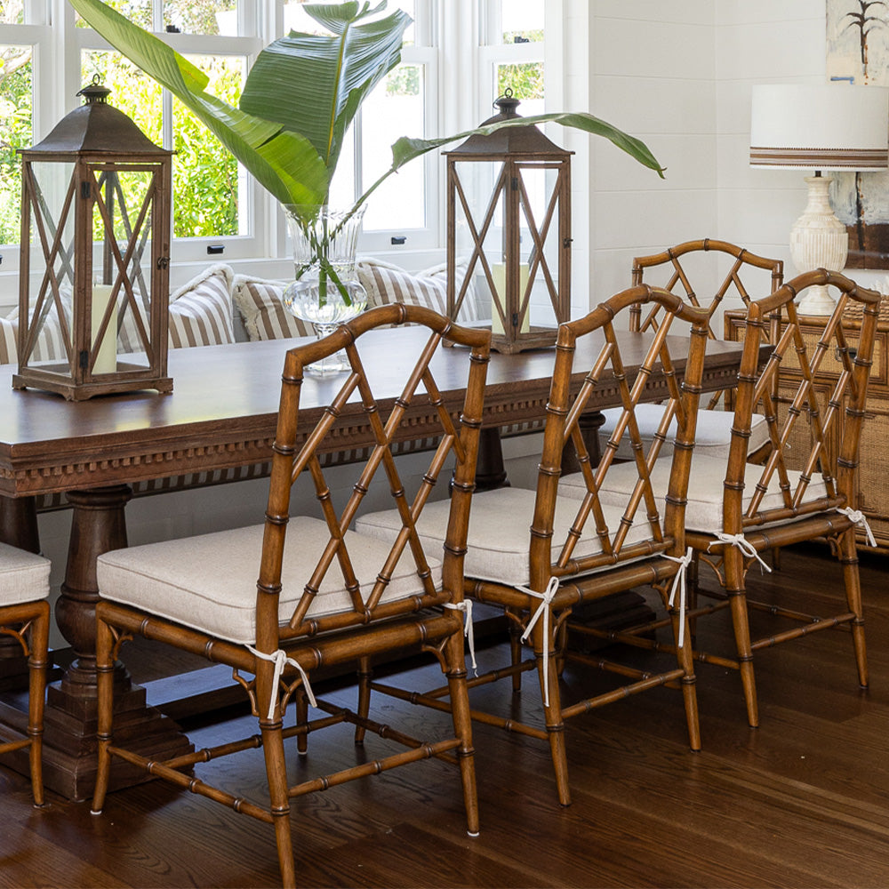 Image of Ralph Dining Chairs at a beach house. The chairs sit at a wooden table styled with two large lanterns. At the other side of the table is a striped fabric bench seat.