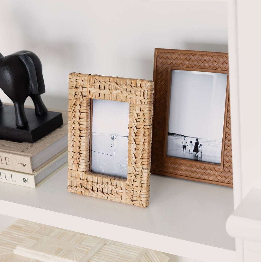 Two wicker picture frames on a white shelf with books and a decorative object.