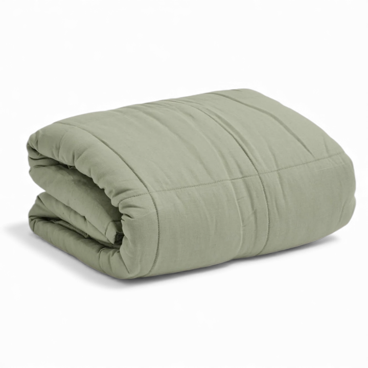 Folded sage green bedspread on a white background