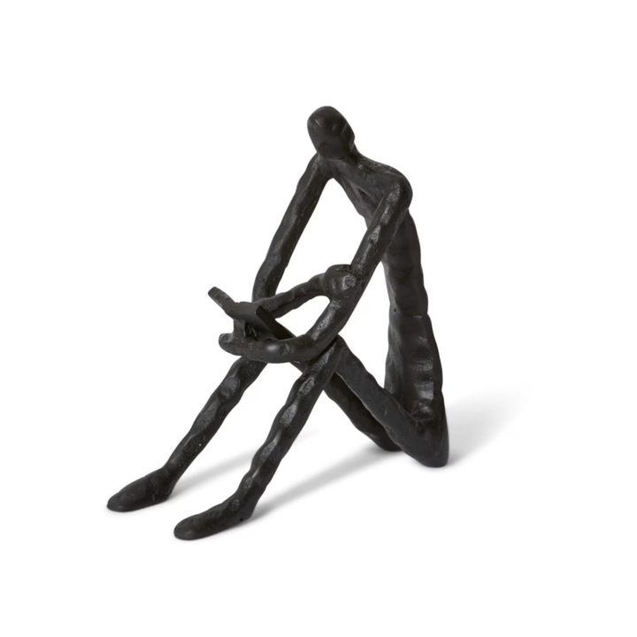 Black abstract sculpture of a seated figure on a white background