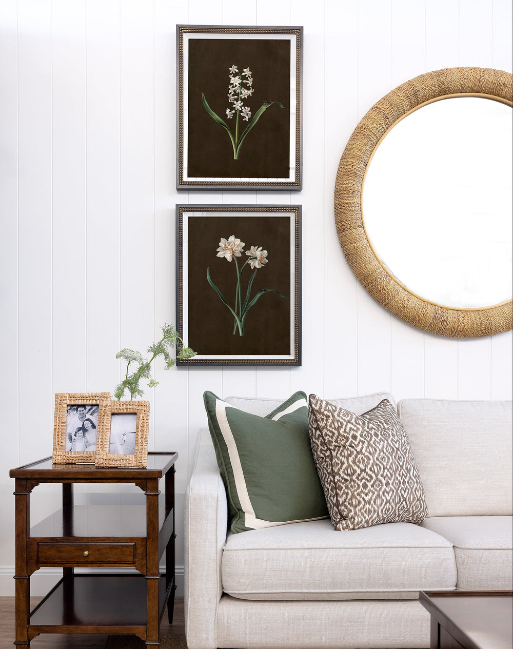 Living room with a white sofa, decorative pillows, framed pictures, and a round mirror.