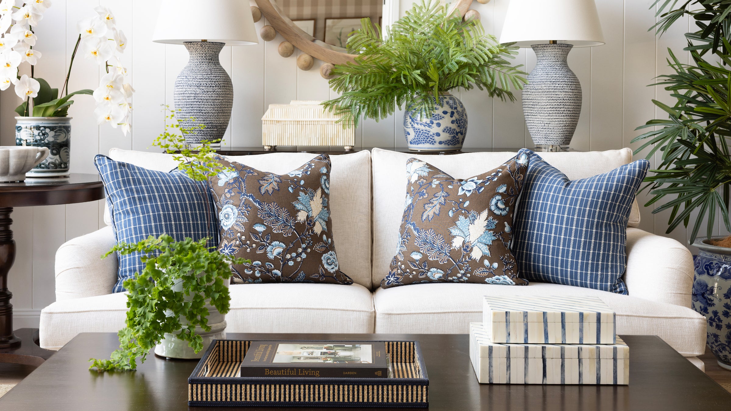 Living room with a white sofa adorned with patterned cushions, a coffee table, and decorative plants.