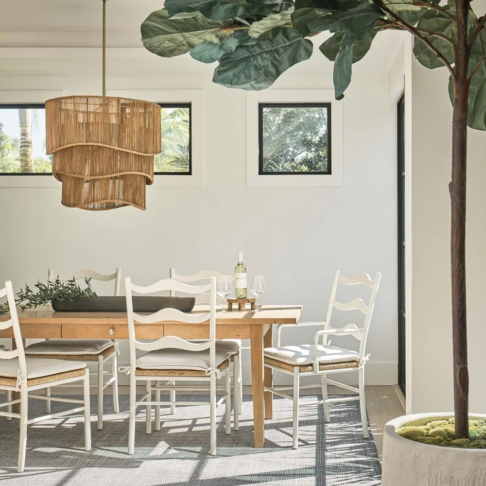Image of white wave chairs around a dining table. Styled with a large faux fiddle leaf fig tree in the front corner, and a large feature woven pendant light in the centre of the table.