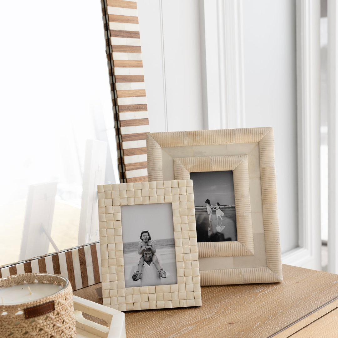 Decorative table with framed photos and a woven basket in a bright room.
