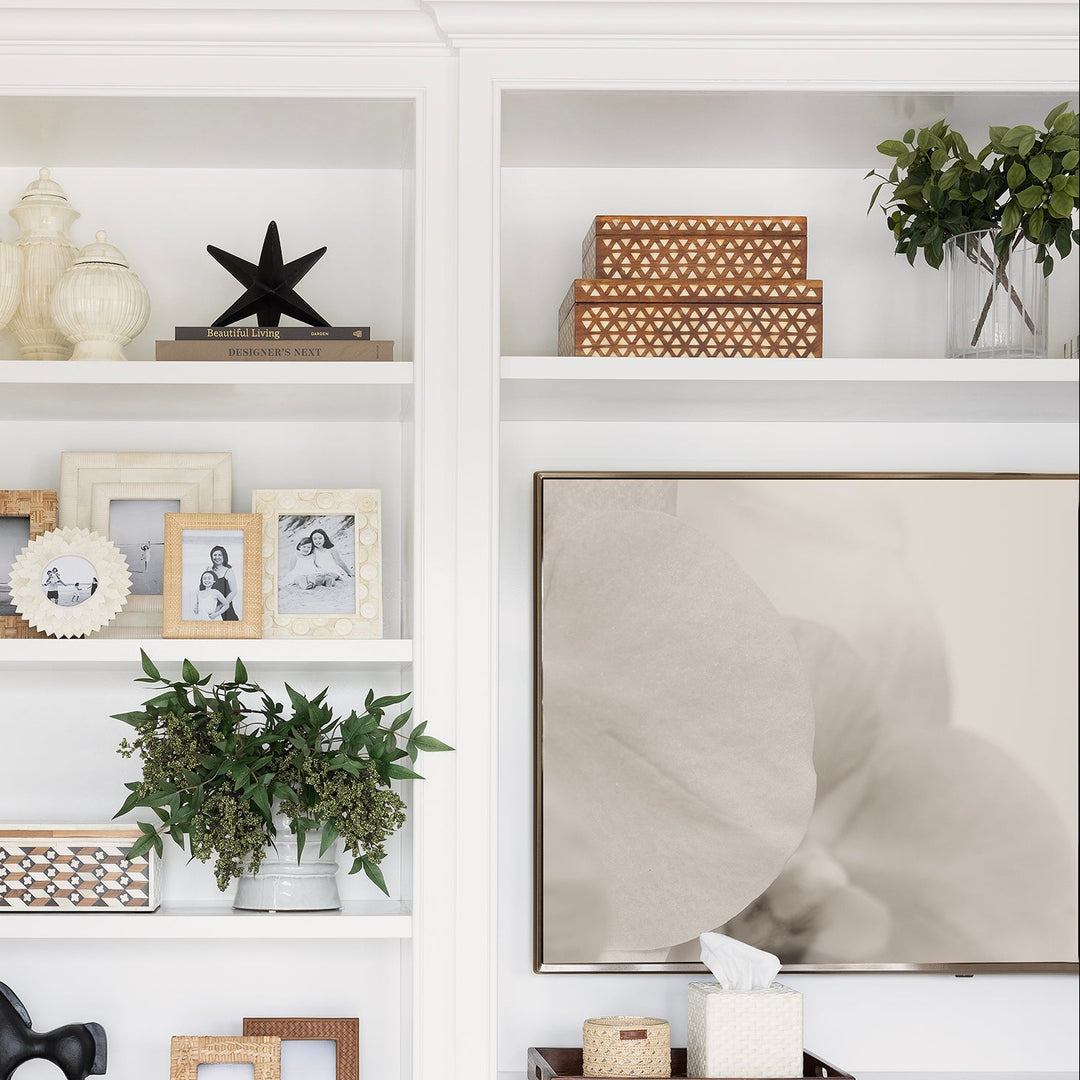 White built-in bookshelf with decorative items in a room with wooden floor and white walls.
