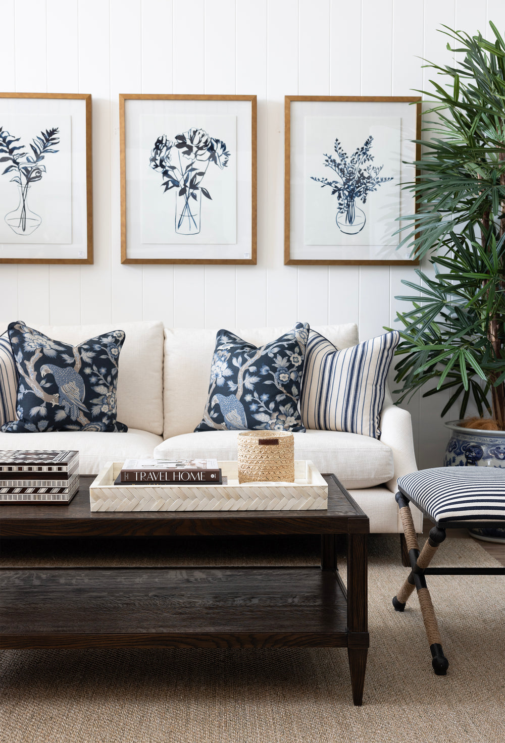 Living room with a white sofa, decorative pillows, a wooden coffee table, and framed botanical prints on the wall.